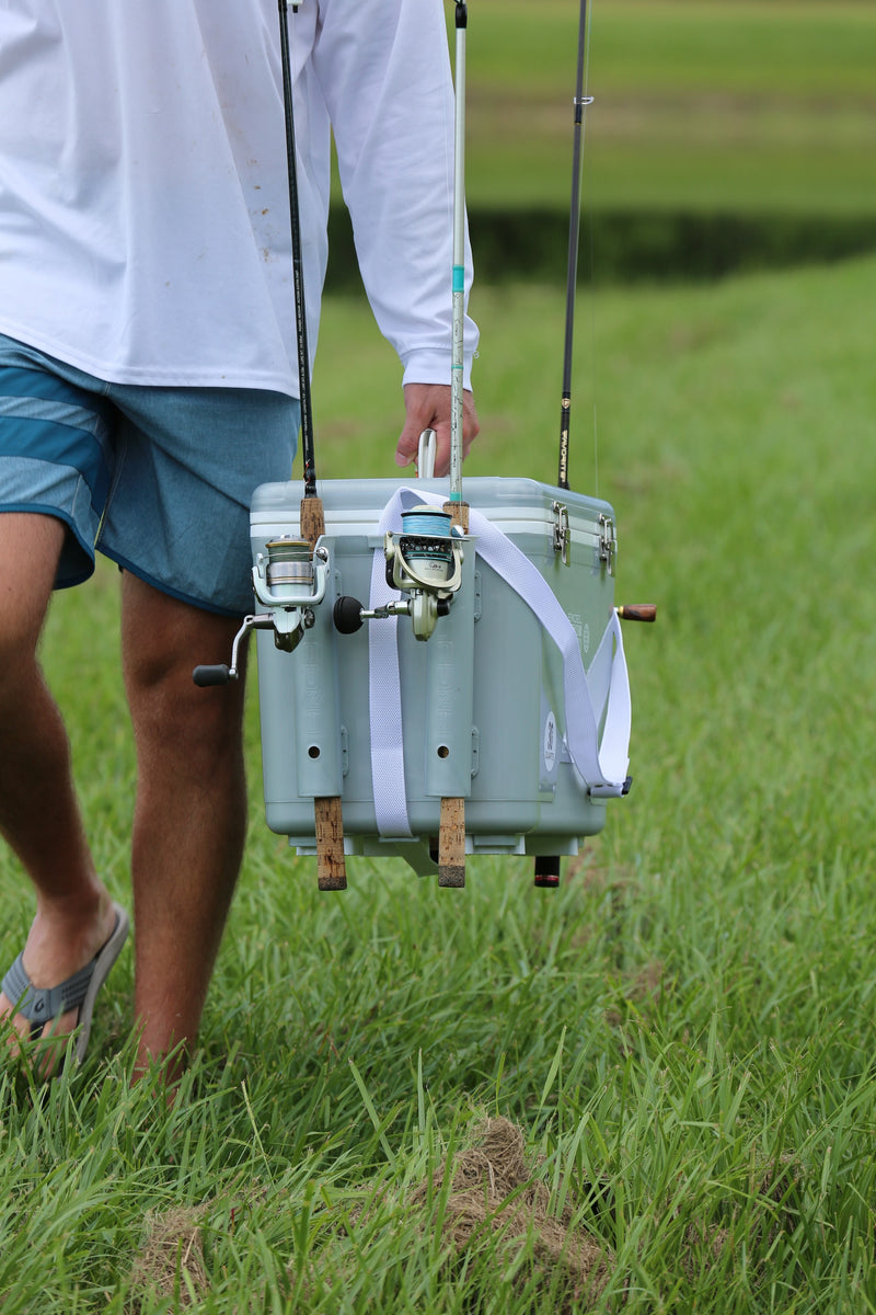 A man carrying two fishing rods and an Engel Coolers 30Qt Live bait Pro Cooler with AP4 XL Rechargeable Aerator, Rod Holders & Stainless Hardware.