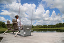 A man sitting on a dock with an Engel Coolers Engel 30Qt Live bait Pro Cooler with AP4 XL Rechargeable Aerator, Rod Holders & Stainless Hardware fishing pole.