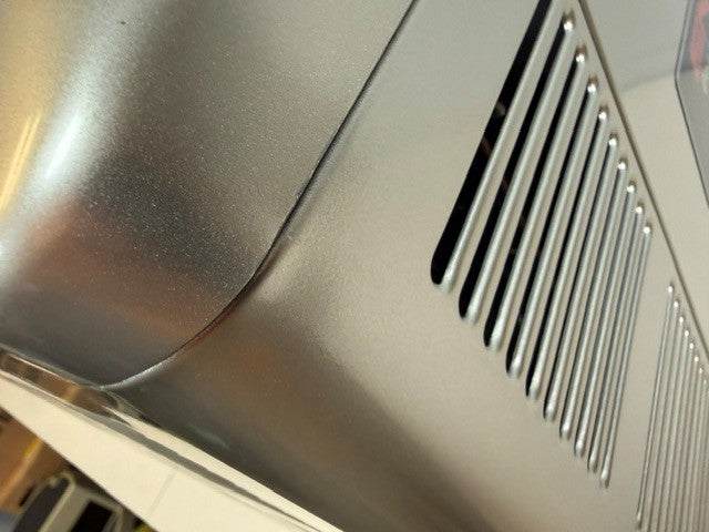 Close-up of an Engel MT45 Combination Platinum Series Top Opening Fridge-Freezer by Engel Coolers, featuring vented slits and a visible dent on its metallic side surface.