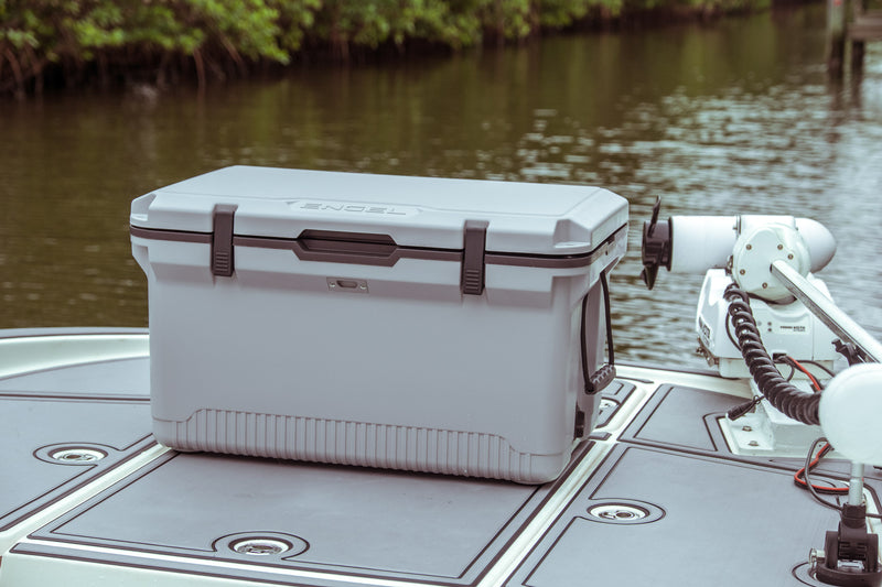 An ice preservation ENGEL 60QT UltraLite Injection-Molded Cooler with Wire Basket and Divider sitting on top of a boat.