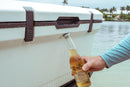 A man is holding a beer, kept chilled in an Engel Coolers 60QT UltraLite Injection-Molded cooler, in the back of a boat.