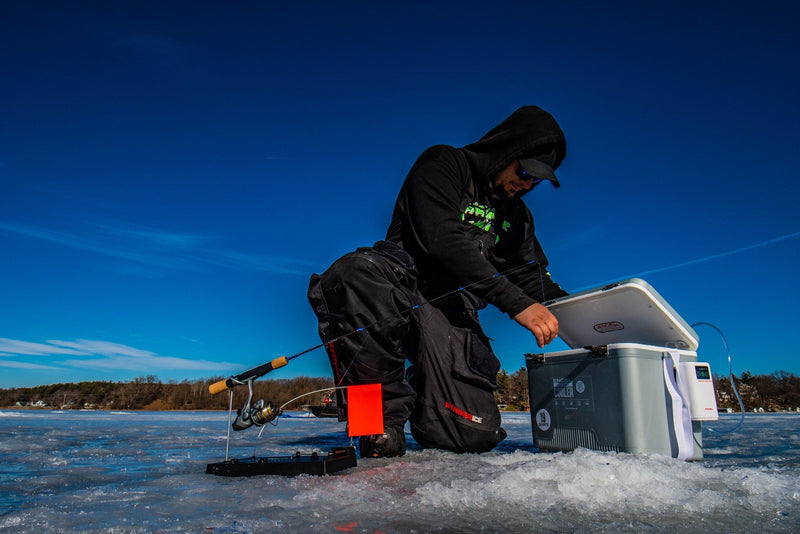 A man holding an Engel Coolers 7.5Qt Live bait Pro Cooler with AP3 Rechargeable Aerator & Stainless Hardware on the ice.