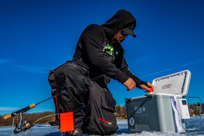 A man is holding an Engel Coolers 19Qt Live bait Pro Cooler with AP3 Rechargeable Aerator & Stainless Hardware on the ice.