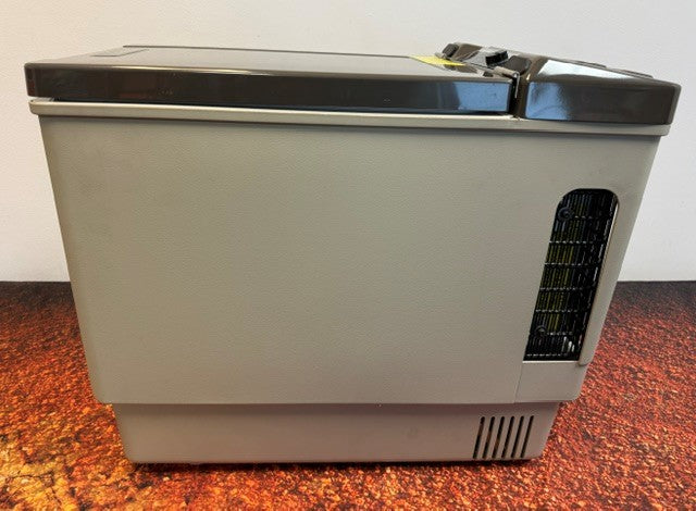 An Engel Coolers Engel MT27 portable fridge-freezer in gray and black rests on a reddish-brown surface, viewed from the side with its vent and closed lid visible.