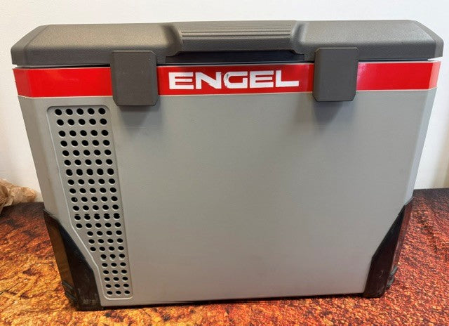 The Engel Coolers MR040 Top Opening Fridge-Freezer, a refurbished portable unit in gray and black with a red stripe and ventilation holes, features a corrosion-resistant ABS case. It rests on a brown textured surface, making it an ideal choice for marine environments.