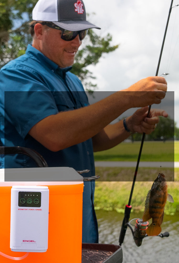 A man holding a fishing pole next to a fish tank.