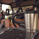 A Engel Coolers 30oz Stainless Steel Vacuum Insulated Tumbler sits on the dashboard of a vehicle.