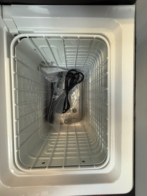 Top-down view of an empty Engel Coolers MT17F fridge-freezer chest, showing its metal wire basket and black power cord inside; supports 12/24V DC and 110/120V AC power.