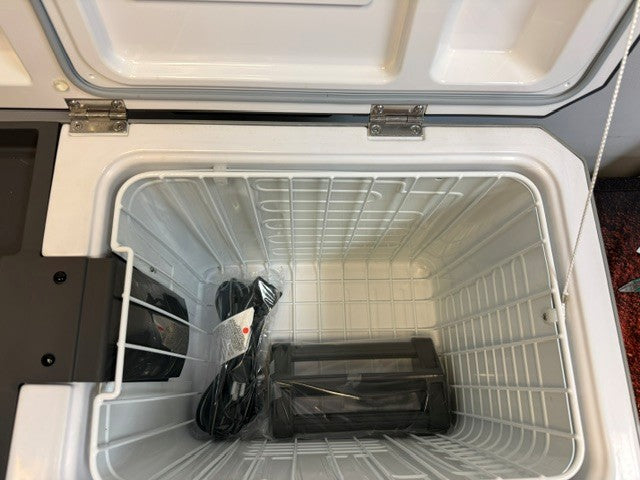 Open the Engel Coolers MR040 Top Opening Fridge-Freezer, featuring a white interior with a power cord and a black rectangular object wrapped in plastic at the bottom—specially designed with corrosion-resistant materials for marine environments.