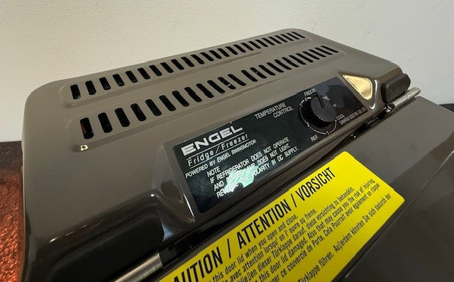 Close-up of the Engel Coolers MT17F top-opening fridge-freezer, featuring its temperature control dial and caution label, powered by a reliable Swing Motor Compressor for efficient performance on 12/24V DC or 110/120V AC.
