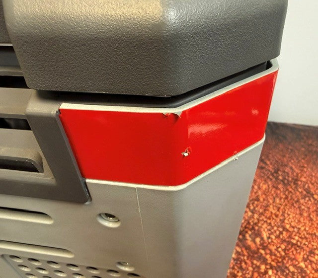 Close-up of a gray and red plastic corner of an Engel Coolers MR040 Top Opening Fridge-Freezer, showing minor scratches and dents on the corrosion-resistant red section.
