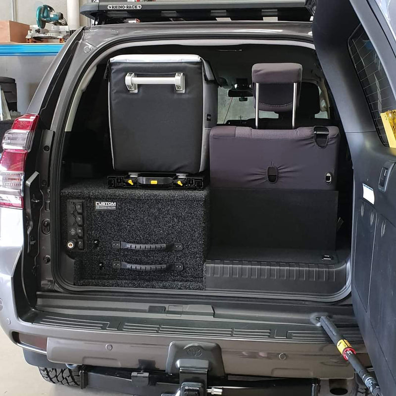 The trunk of an SUV with luggage and an ENGEL Low-Profile Front-Pull Tilt Fridge Slide in it.