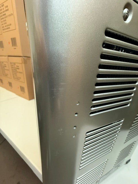 Close-up of the side and back of a metallic Engel Coolers MT45 Platinum Series (Refurbished) portable fridge-freezer, featuring ventilation slits, positioned next to a stack of cardboard boxes on a white table.