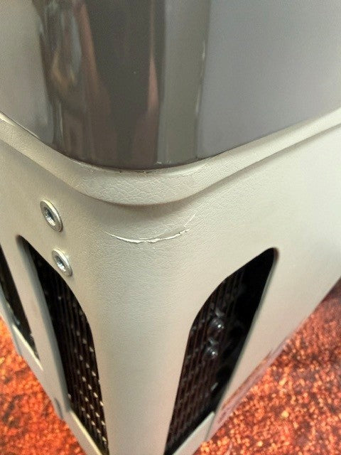 Close-up of a gray plastic component from the Engel MT27 by Engel Coolers, showing a visible crack near the corner next to black vent openings and metal screws. This portable fridge-freezer exemplifies the durability of its Swing Motor compressor design.