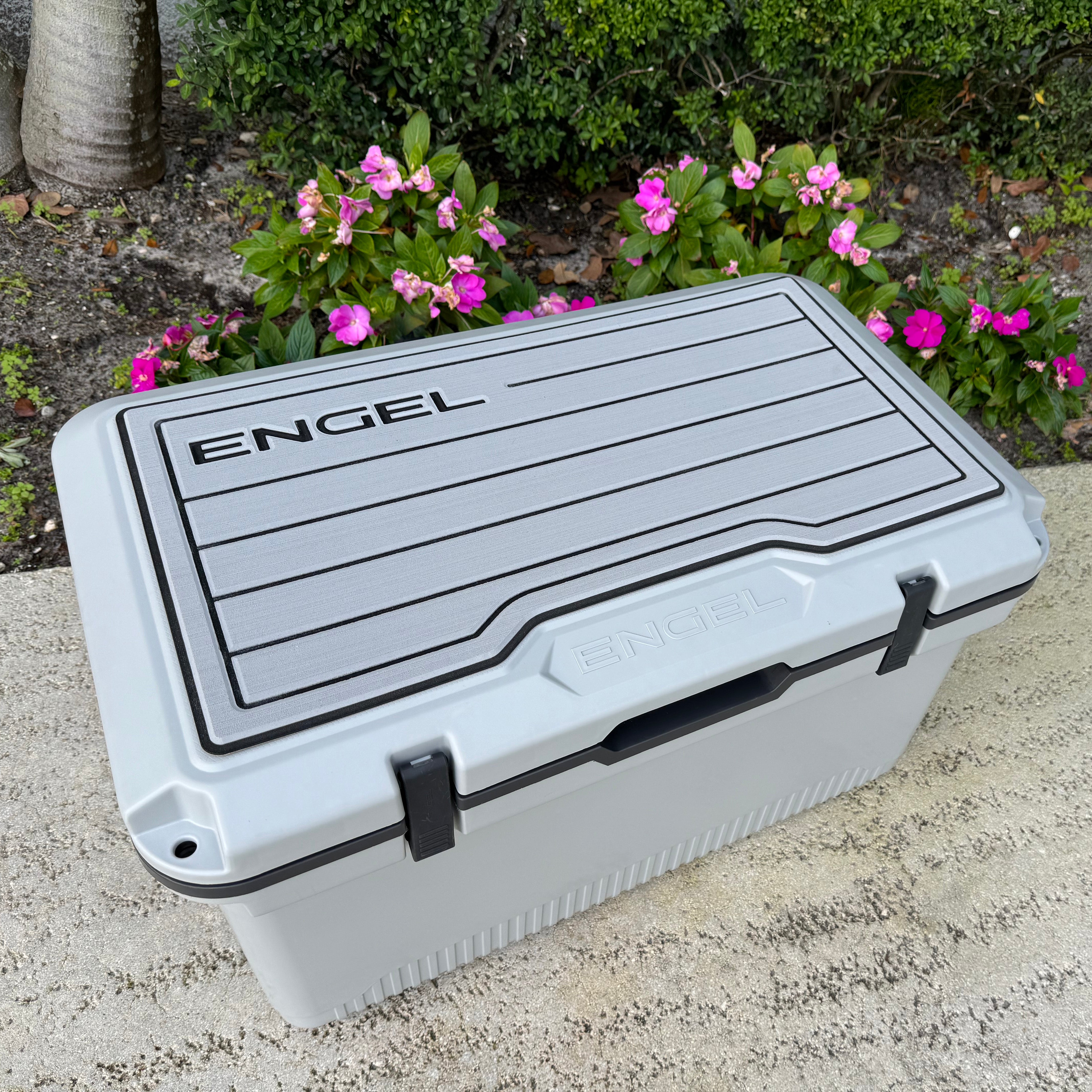 An Engel UL60 SeaDek Non-Slip Marine Cooler Topper sitting on a concrete slab.