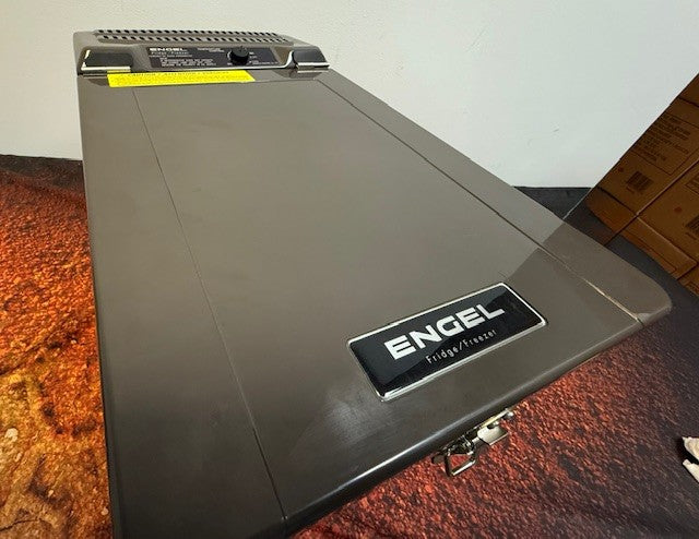 An Engel Coolers MT17F top-opening fridge-freezer with a closed lid and swing motor compressor is seen from an angle on a patterned surface. Suitable for 12/24V DC and 110V/120V AC.