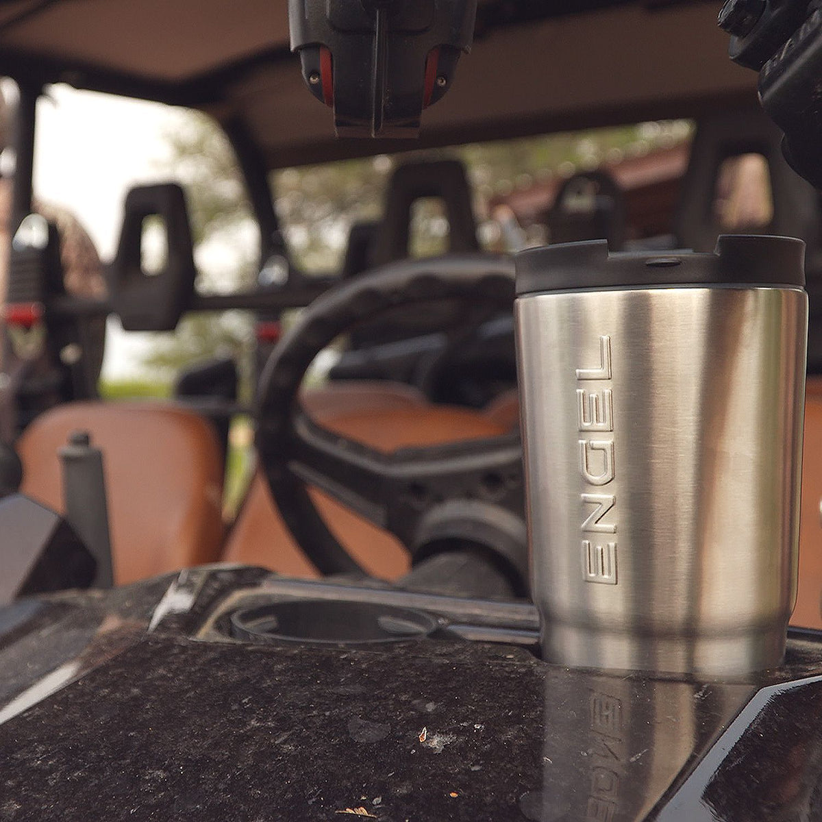 A vacuum-insulated Engel 30oz Black Stainless Steel Tumbler sits on the dashboard of a vehicle.