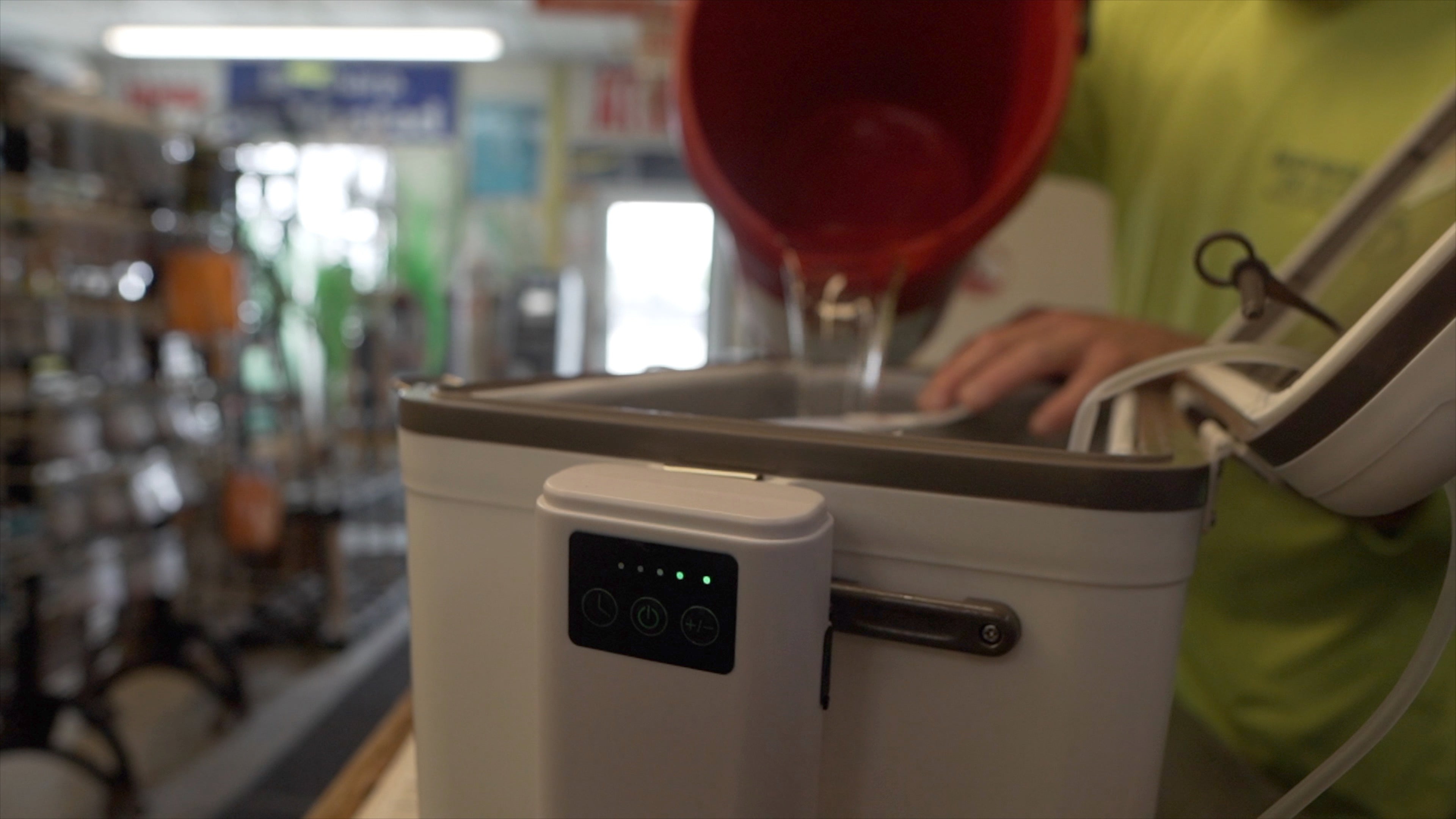 A man pouring a liquid into a rechargeable Engel Coolers Lithium-ion Rechargeable Live Bait Aerator Pump.