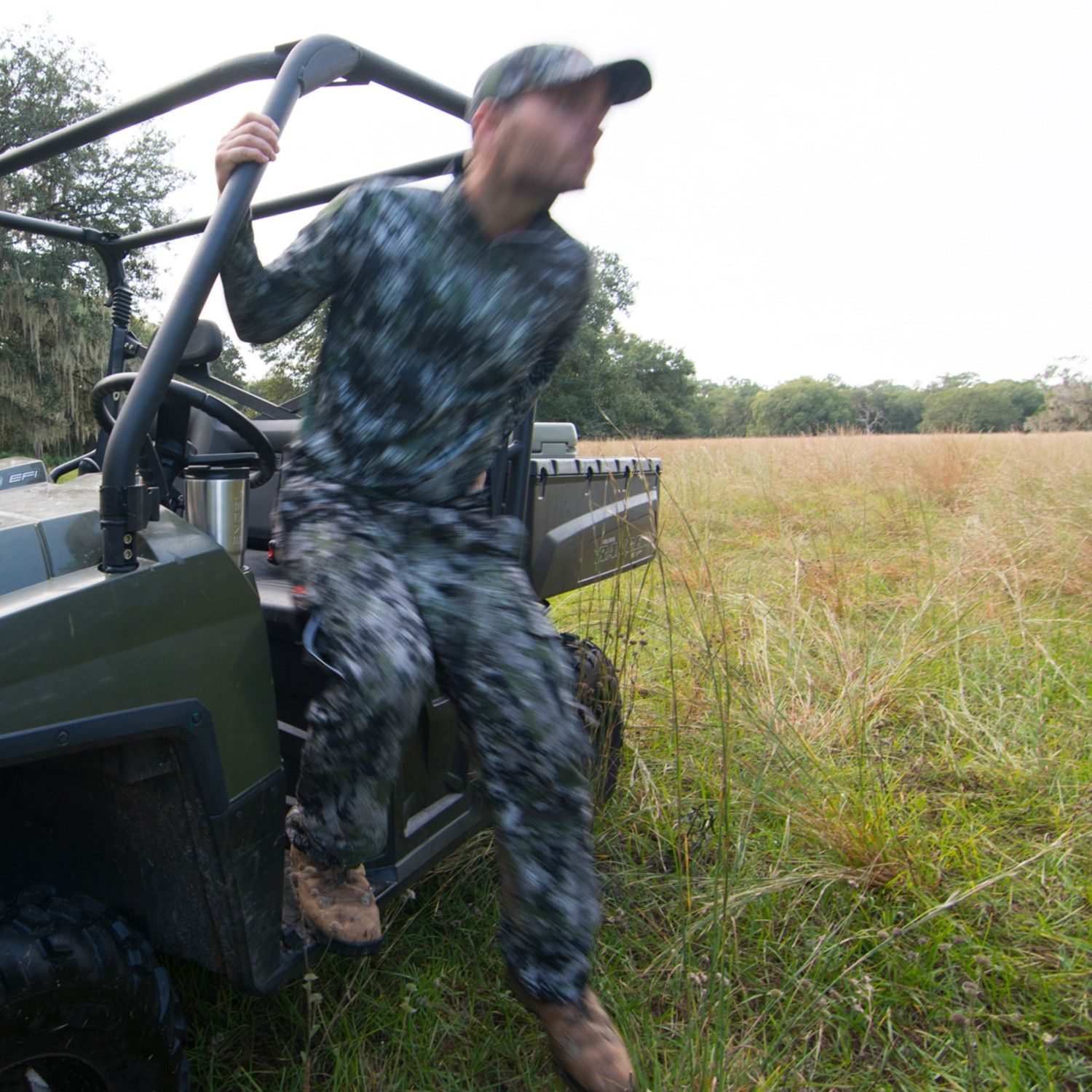 A man riding an ATV in a field sporting an Engel 30oz PRYM1 Camo Tumbler.