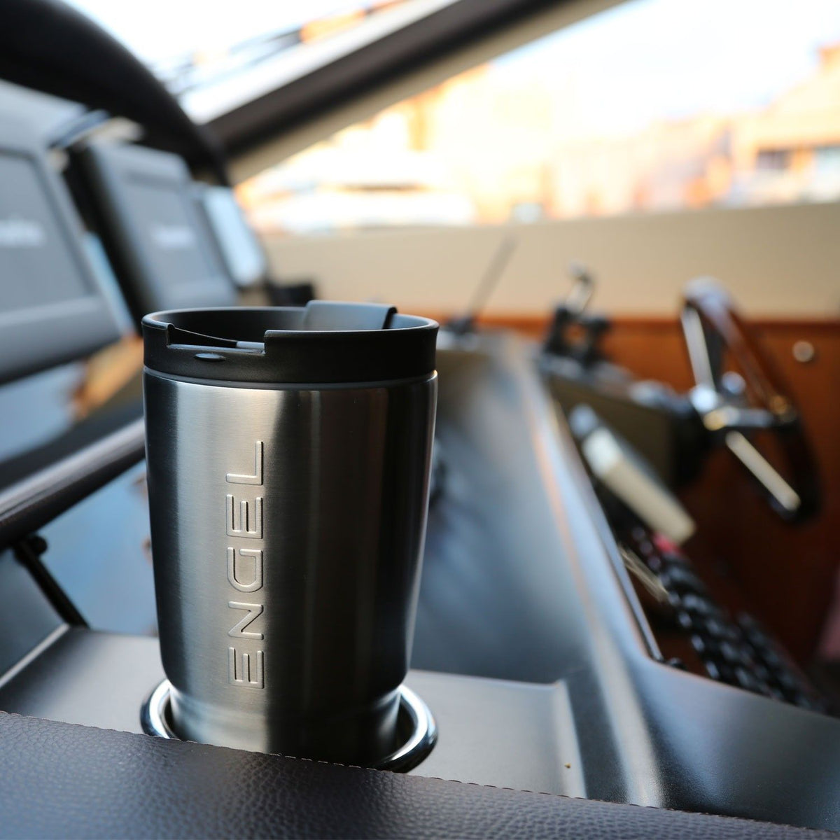 A Engel Coolers 30oz Black Stainless Steel Tumbler on the dashboard of a boat.