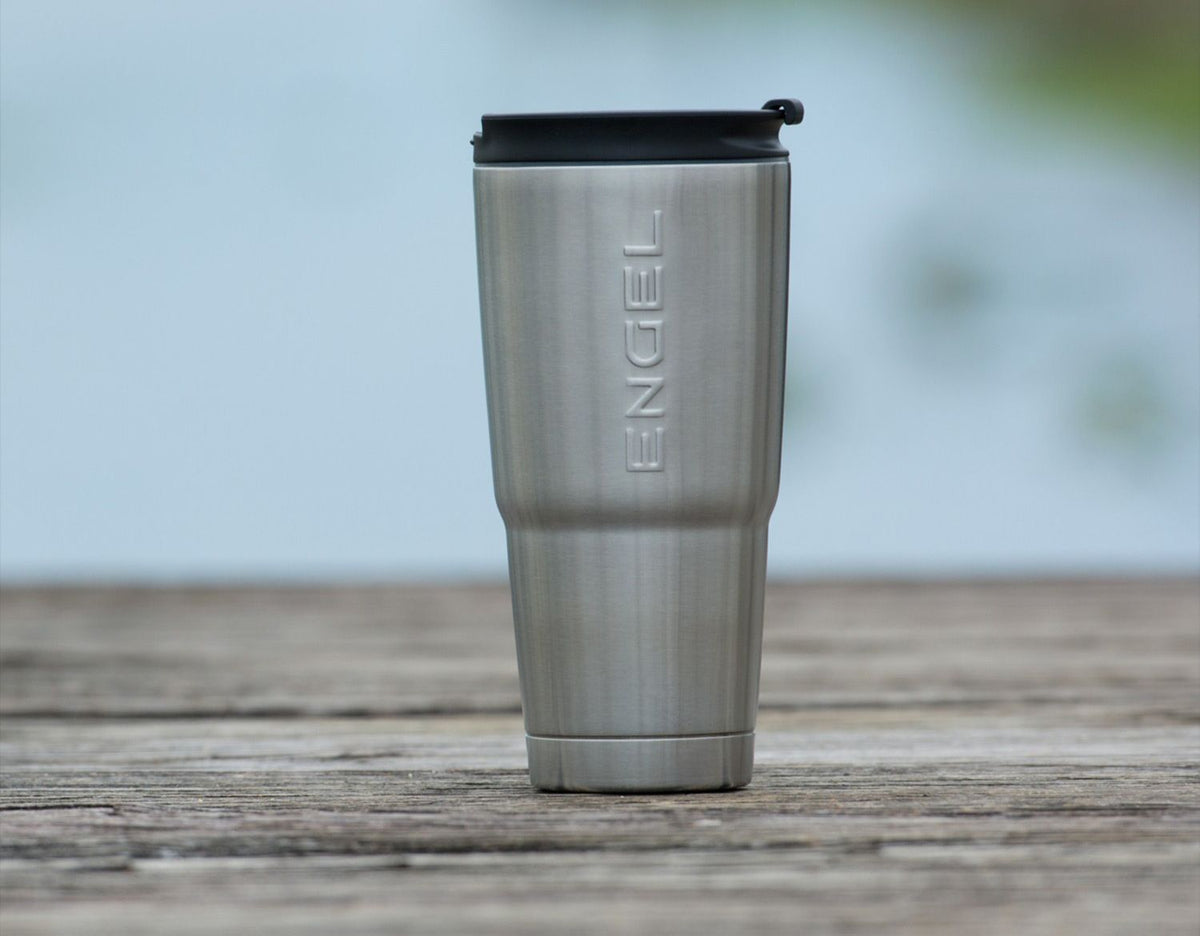 A Engel 30oz Black Stainless Steel Tumbler with a liquid-tight lid sits on a wooden table.